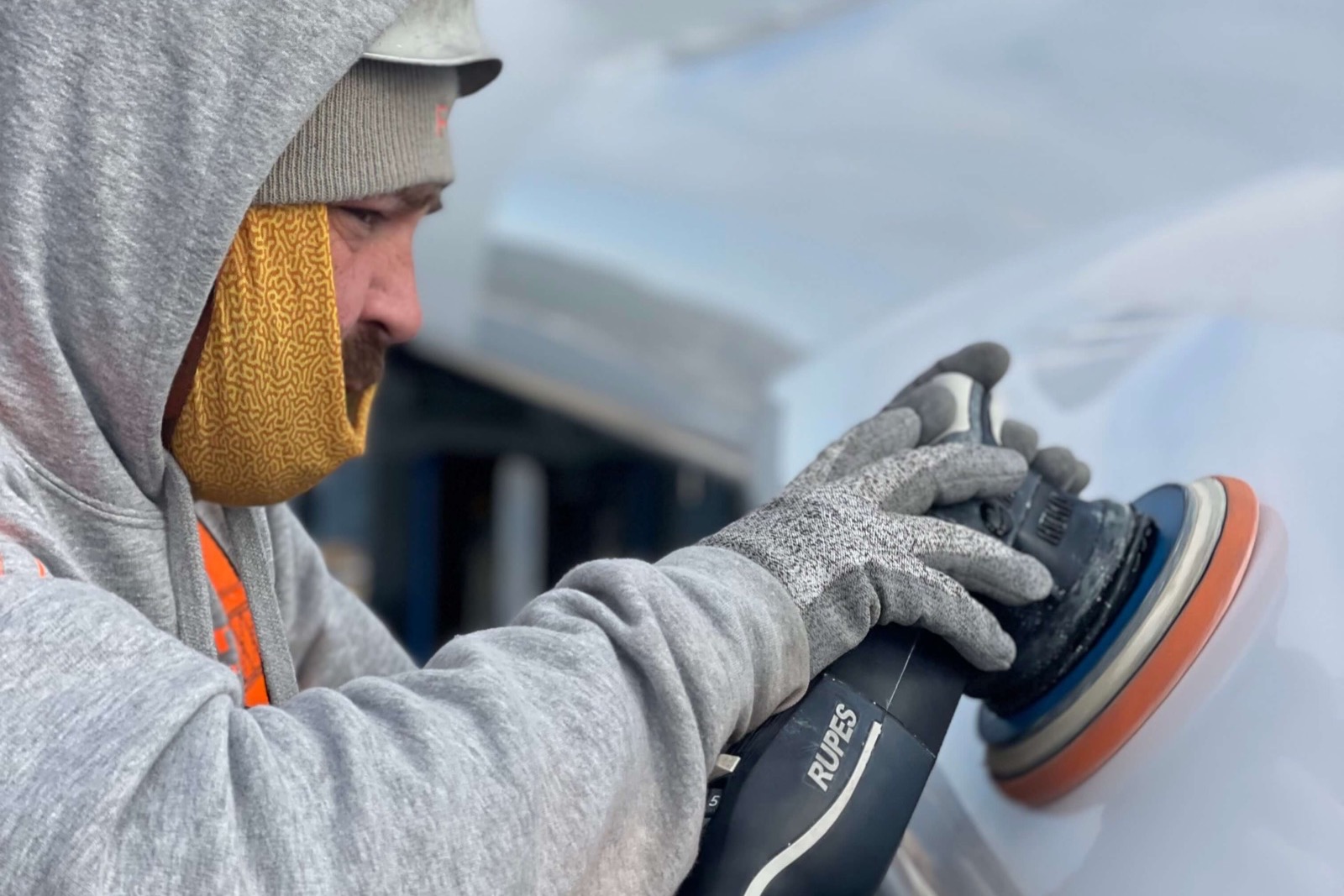 An RMP Marine technician working a rotary polisher across a superyacht hull.