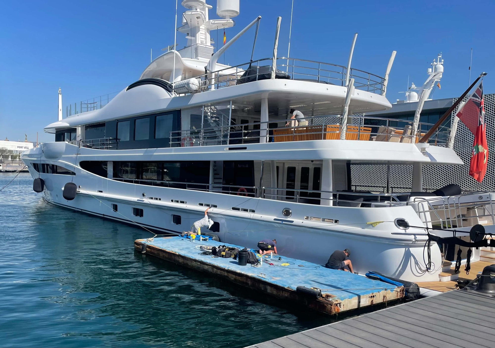 An RMP Marine team working along the topsides of a superyacht from a floating platform.
